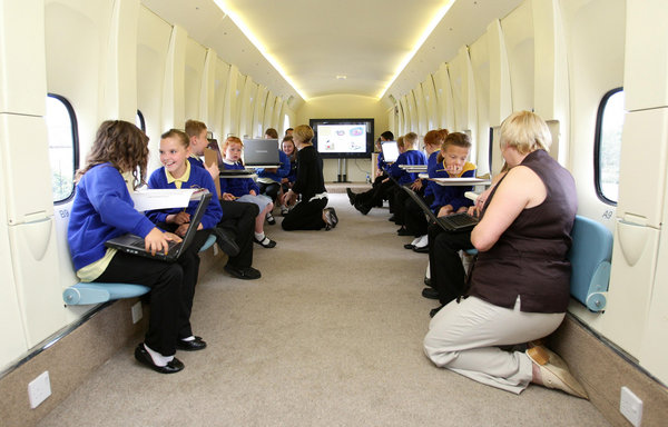 Year 3 and year 4 pupils from Kingsland Primary School in Stoke on Trent, with the plane they use as a classroom. [CFP]