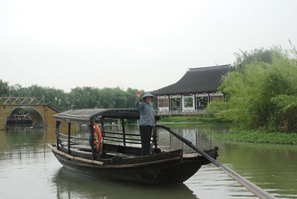 Huang Xingbao, a 62-year old boat lady, waves goodbye to reporters from CRI on Wednesday, July 15, 2009. She attracted the press through her unique performance of singing folk songs while rowing a wooden boat. [Photo: CRIENGLISH.com]