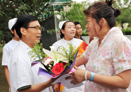 Yao Lumei (R), who was wounded in the July 5 riot, presents flowers to doctor Zhang Dekuan for his careful attendance before she leaves the hospital in Urumqi, capital of northwest China's Xinjiang Uygur Autonomous Region, July 15, 2009. Twelve of the twenty-two people who received treatment in the 23rd Hospital of the People's Liberation Army (PLA) after being wounded in the July 5 riot in Urumqi left the hospital on Wednesday as they recovered from the wounds.