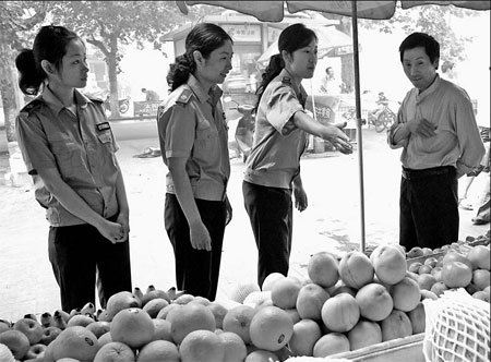 Three female chengguan officers ask a fruit vendor to put away goods at his stall in Donghai county, Lianyungang city of Jiangsu province on June 15. To ease the tension between the vendors and chengguan officers, the county established a chengguan team of 10 women in June to patrol the county's downtown areas.