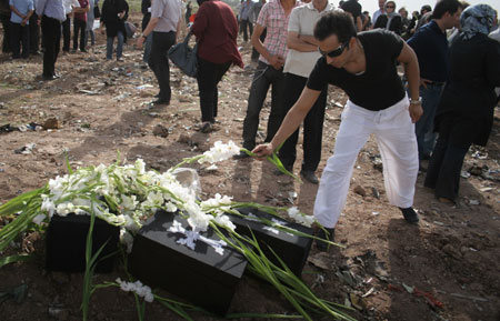 A man offers a bunch of flower to the mocked coffins to mourn for the victims of the crashed Tupolev Caspian airplane in Qazvin, northwestern Iran, July 16, 2009. [Ahmad Halabisaz/Xinhua]