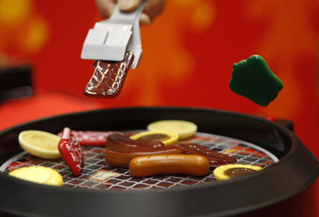 A person demonstrates how to play Japanese toymaker MegaHouse's 'Yakinikuo', meaning 'King of Grilled Beef', at the International Tokyo Toy Show, July 16, 2009. The game in which players compete to pick as many pieces of 'food' jumping on a grill-like platform will be displayed at the toy show, which runs until July 19. [Xinhua/Reuters]