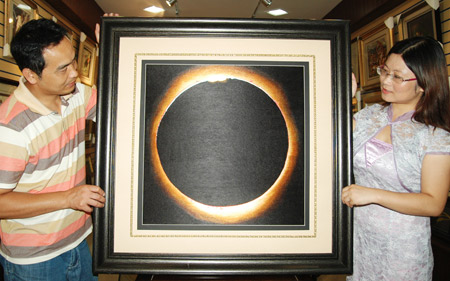 Chen Yinghua (R) shows her embroidery 'Total Solar Eclipse' in Suzhou City of east China's Jiangsu Province, July 7, 2009. Recently finished by embroidery master Chen Yinghua after a total of 120 days' work, the embroidery 'Total Solar Eclipse' will be displayed on an academic meeting on solar coronal dynamics hosted by the International Astronomical Union in Suzhou. [Zhu Guigen/Xinhua]