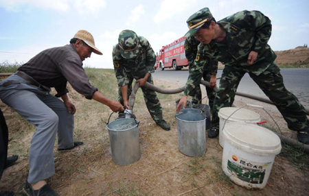 Chinese firemen deliver water to farmers in the drought-hit Tuanjie Village, Huining County, in northwest China's Gansu province, July 15, 2009. There has been almost no rain since January this year in Huining, leaving the county’s 160,000 residents and 226,000 livestock without enough water. [Xinhua]