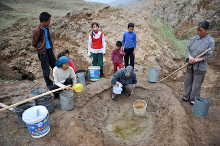 Farmers wait to collect water from a shallow well in Tuanjie Village, Huining County, in northwest China's Gansu province, July 15, 2009. There has been almost no rain since January this year in Huining, leaving the county’s 160,000 residents and 226,000 livestock without enough water. [Xinhua]