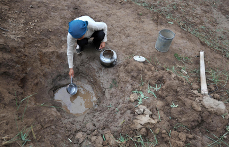 A farmer collects water from a shallow well in Tuanjie Village, Huining County, in northwest China's Gansu province, July 15, 2009. There has been almost no rain since January this year in Huining, leaving the county’s 160,000 residents and 226,000 livestock without enough water. [Xinhua]