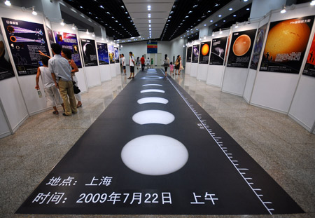 Local citizens watch the sketch maps illustrating the whole process of the full solar eclipse, during a popular science exhibition on the introduction to the forthcoming 2009 Full Solar Eclipse at the Shanghai Science and Technology Museum, in Shanghai, east China, July 11, 2009.