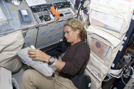 In this photo released by NASA, Canadian Space Agency astronaut Julie Payette, STS-127 mission specialist, reads a procedures checklist on the aft flight deck of Space Shuttle Endeavour during flight day two activities July 16, 2009.[Xinhua/Reuters]