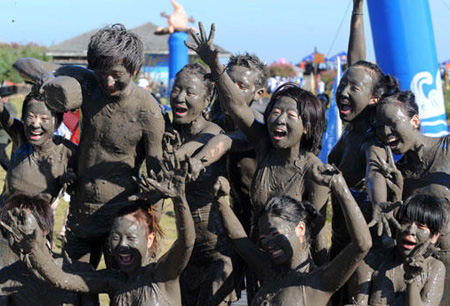 Tourists play with sea mud at a park in Xiushan Island, Daishan county, east China's Zhejiang province, Friday, July 17, 2009. Thousands of tourists from across China and local residents join the sea mud carnival in the park to fend off the sizzling heat in the summer. [Xinhua]