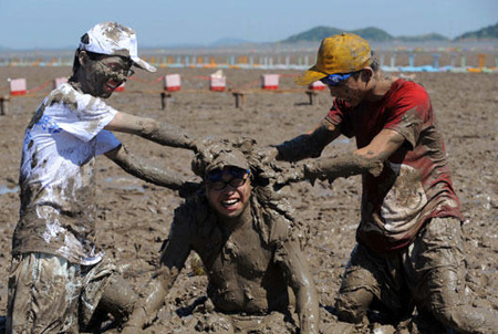 Tourists play with sea mud at a park in Xiushan Island, Daishan county, east China's Zhejiang province, Friday, July 17, 2009. [Xinhua]