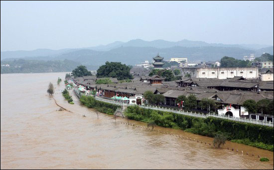 The flood inundated the dykes and dams in Langzhoung City in Sichuan Province on July 17. Four days of torrential rains and floods have killed at least eight people in Sichuan Province and two in Gansu Province by July 17. [Xinhua]