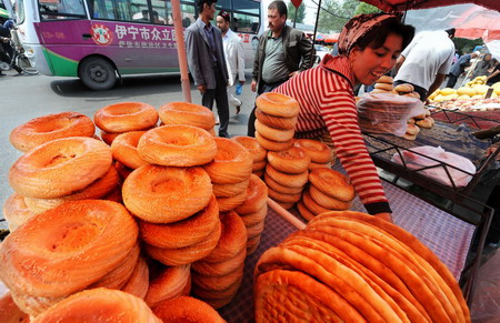 A vendor prepares a traditional local bread known as nang at a bazaar on Han Ren Jie in Yining, in northwest China's Xinjiang Uygur autonomous region, July 19, 2009. [Xinhua]
