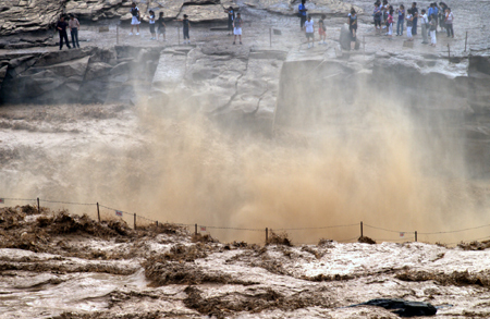 Tourists view the Hukou Waterfall of the Yellow River in northwest China's Shaanxi Province, July 18, 2009. Recent rainfalls on the upper reaches of the Yellow River have brought a heavy load of sediment in the form of sand and mud, making the water yellower than usual. [Xinhua]