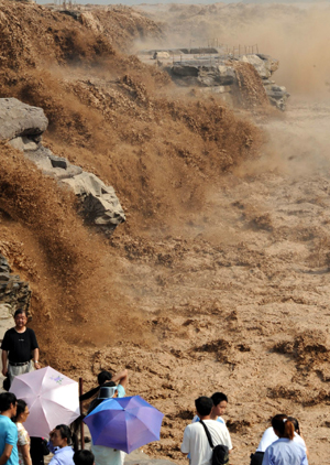 Tourists view the Hukou Waterfall of the Yellow River in northwest China's Shaanxi Province, July 18, 2009. Recent rainfalls on the upper reaches of the Yellow River have brought a heavy load of sediment in the form of sand and mud, making the water yellower than usual. [Xinhua]