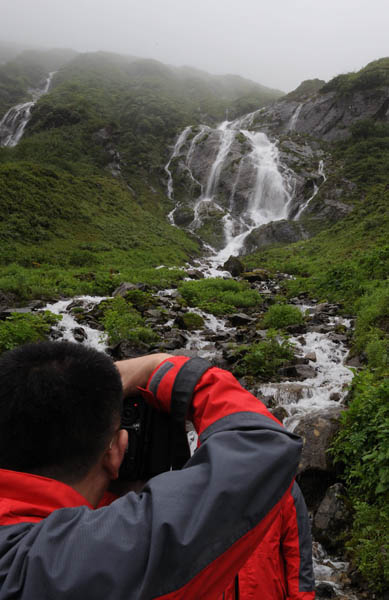 Visitors take photos by the waterfall. [Photo: Xinhuanet]