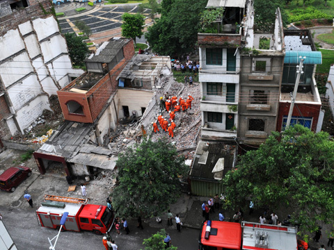 Rescuers rush to the site after the three-story building, which was to be dismantled to make way for a park, collapsed at about 8:40 AM Monday, July 20, 2009 in Liuzhou City, Guangxi, killing two people instantly. [Photo: CRIENGLISH.com]
