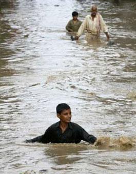 A boy wades through flood waters outside his home in Karachi July 19, 2009. [RAkhtar Soomro/CCTV/EUTERS] 