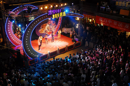 People stage shows on the square in Yuyuan of Shanghai, east China, July 20, 2009. A month-long summer leisure festival was opened in Yuyuan, a famous garden in Shanghai on Junly 18. The festival provides a favorable place for local residents to spent hot summer nights with lamp shows and folk culture shows. [Xinhua]