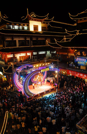 People stage shows on the square in Yuyuan of Shanghai, east China, July 20, 2009. A month-long summer leisure festival was opened in Yuyuan, a famous garden in Shanghai on Junly 18. The festival provides a favorable place for local residents to spent hot summer nights with lamp shows and folk culture shows. (Xinhua) 