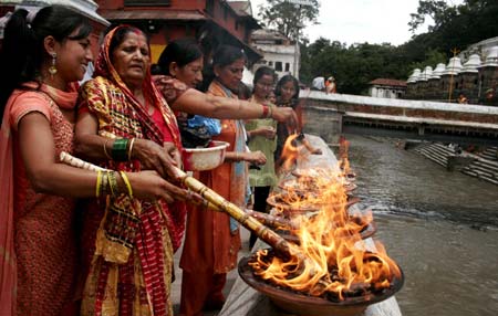 Nepalese Hindu women perform rituals for the Hindu god Lord Shiva, the god of destruction, at the Pashupati temple in Kathmandu, capital of Nepal, July 20, 2009. Hundreds of Hindu women gathered at the Pashupati temple in Kathmandu, the world heritage site, on the first Shrawan Somvar (Monday) of the Nepalese calender Shrawan (July 15 - August 15) to offer holy water to Lord Shiva. Shrawan month is considered as the holiest month of the year and each Somvar (Monday) of this month known as Shrawan Somvar is special day in Shiva temples. Hindu women wear red attire as well as green and yellow bangles, pray for the long and prosperous life for their husbands. (Xinhua/Bimal Gautam)