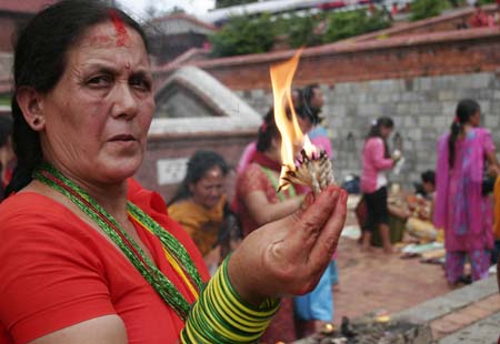 A Nepalese Hindu woman lights lamp while worshiping Lord Shiva, the god of destruction, at the Pashupati temple in Kathmandu, capital of Nepal on July 20, 2009. Hundreds of Hindu women gathered at the Pashupati temple in Kathmandu, the world heritage site, on the first Shrawan Somvar (Monday) of the Nepalese calender Shrawan (July 15 - August 15) to offer holy water to Lord Shiva. Shrawan month is considered as the holiest month of the year and each Somvar (Monday) of this month known as Shrawan Somvar is special day in Shiva temples. Hindu women wear red attire as well as green and yellow bangles, pray for the long and prosperous life for their husbands. (Xinhua/Bimal Gautam)