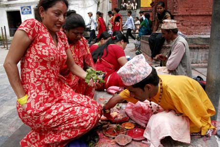 Nepalese Hindu women perform rituals for the Hindu god Lord Shiva, the god of destruction, at the Pashupati temple in Kathmandu, capital of Nepal, July 20, 2009. Hundreds of Hindu women gathered at the Pashupati temple in Kathmandu, the world heritage site, on the first Shrawan Somvar (Monday) of the Nepalese calender Shrawan (July 15 - August 15) to offer holy water to Lord Shiva. Shrawan month is considered as the holiest month of the year and each Somvar (Monday) of this month known as Shrawan Somvar is special day in Shiva temples. Hindu women wear red attire as well as green and yellow bangles, pray for the long and prosperous life for their husbands. (Xinhua/Bimal Gautam)