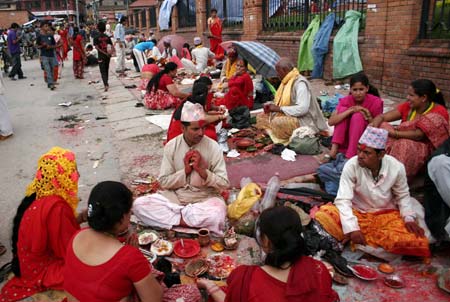 Nepalese Hindu women perform rituals for the Hindu god Lord Shiva, the god of destruction, at the Pashupati temple in Kathmandu, capital of Nepal, July 20, 2009. Hundreds of Hindu women gathered at the Pashupati temple in Kathmandu, the world heritage site, on the first Shrawan Somvar (Monday) of the Nepalese calender Shrawan (July 15 - August 15) to offer holy water to Lord Shiva. Shrawan month is considered as the holiest month of the year and each Somvar (Monday) of this month known as Shrawan Somvar is special day in Shiva temples. Hindu women wear red attire as well as green and yellow bangles, pray for the long and prosperous life for their husbands. (Xinhua/Bimal Gautam)