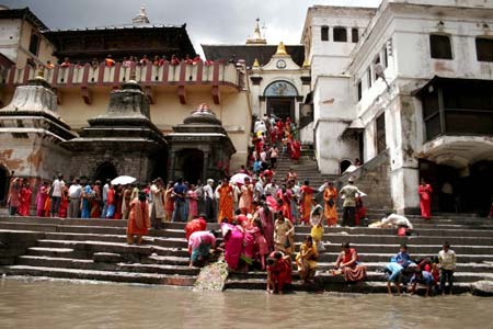 Nepalese Hindu devotees line up to offer prayers to the Hindu god Lord Shiva, the god of destruction, at the Pashupati temple in Kathmandu, capital of Nepal, July 20, 2009. Hundreds of Hindu women gathered at the Pashupati temple in Kathmandu, the world heritage site, on the first Shrawan Somvar (Monday) of the Nepalese calender Shrawan (July 15 - August 15) to offer holy water to Lord Shiva. Shrawan month is considered as the holiest month of the year and each Somvar (Monday) of this month known as Shrawan Somvar is special day in Shiva temples. Hindu women wear red attire as well as green and yellow bangles, pray for the long and prosperous life for their husbands. (Xinhua/Bimal Gautam) 