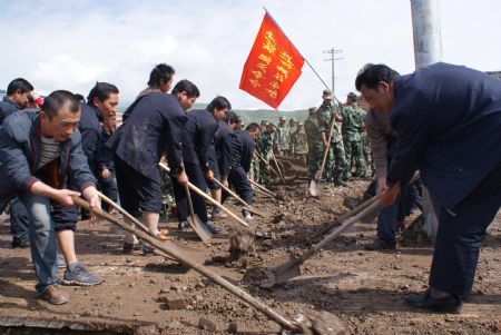 Local Chinese and armed police officers clear mud left by a flood on a road July 21, 2009 after a heavy rainstorm hit Maqu County in northwest China's Gansu province, killing at least five people. [Liang Jianming/Xinhua]