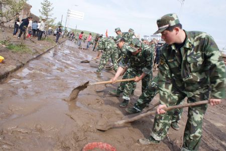 Chinese armed police officers clear mud left by a flood on a road July 21, 2009 after a heavy rainstorm hit Maqu County in northwest China's Gansu province, killing at least five people. [Liang Jianming/Xinhua]