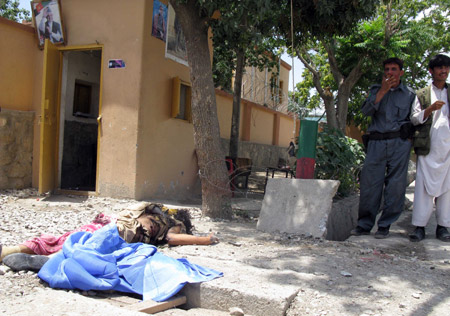 Two Afghan policemen stand near the body of a suicide bomber killed by security personnel in Gardiz of Paktia Province, southeastern Afghanistan, July 21, 2009. Nine suicide bombers launched attacks in two provinces of Afghanistan on Tuesday, three of them in Nangarhar Province and six others in Gardiz of Paktia Province in an attempt to target governmental institutions. The attacks left 10 people dead and two policemen injured. (Xinhua/Stringer)