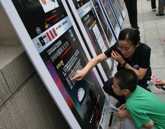 A Beijing Planetarium staff member explains the cause of the solar eclipse to a boy on the morning of July 22 2009. Some areas in south China witnessed a full solar eclipse on that day. But people in Beijing only saw a partial eclipse. 