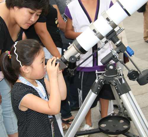 : A little girl watches a solar eclipse through a telescope at Beijing Planetarium on the morning of July 22 2009. Some areas in south China witnessed a full solar eclipse on that day. But people in Beijing only saw a partial eclipse. 