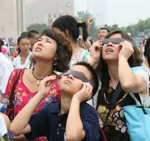 People watch a solar eclipse outside Beijing Planetarium on July 22 2009. Some areas in south China witnessed a full solar eclipse on that day. But people in Beijing only saw a partial eclipse. 