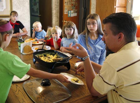 Jeub family members listen to father Chris (R) before breakfast in the kitchen of the family home in Monument, Colorado July 17, 2009. (L-R) Keilah, 8; Lydia, 15; Joshua, 3; Josiah, 5; Hannah, 6; Cynthia, 17 and Chris.