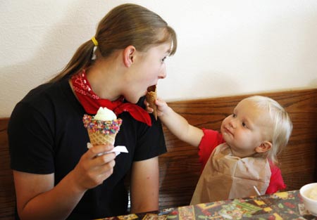 Lydia Jeub (L) shares an ice cream cone offered by one-year-old sister Priscilla during an outing near Monument, Colorado July 17, 2009.