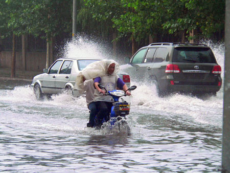 Vehicles and cyclists drive in water after a heavy rain hit Beijing, capital of China, July 22, 2009. A summer heavy rain hit China's capital city Wednesday evening. 
