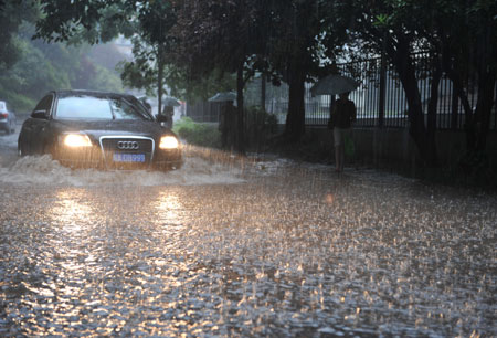 A vehicle moves on a flooded street as a heavy rain hits Hefei, capital city of east China's Anhui Province, July 23, 2009. [Yang Xiaoyuan/Xinhua]