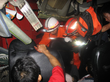 Firefighters rescue the injured passengers trapped in a car at the scene of a car accident on an expressway in Qianxi County, southwest China's Guizhou Province, on July 24, 2009. At least four people died and more than 40 others were injured after a bus-truck collision in wee hours on Friday in Qianxi County, according to local traffic authorities.(Xinhua)