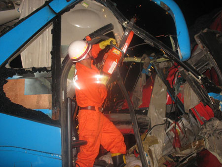 Firefighters rescue the injured passengers trapped in a car at the scene of a car accident on an expressway in Qianxi County, southwest China's Guizhou Province, on July 24, 2009. At least four people died and more than 40 others were injured after a bus-truck collision in wee hours on Friday in Qianxi County, according to local traffic authorities. (Xinhua)