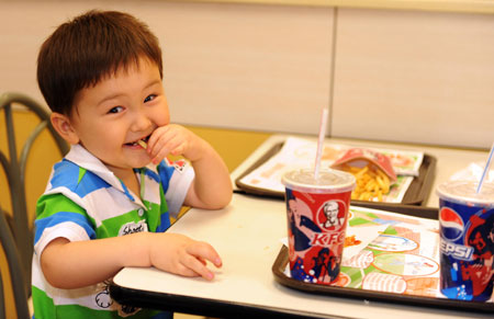 A kid eats at the KFC store in the international bazar in Urumqi, capital of northwest China's Xinjiang Uygur Autonomous Region, July 23, 2009. The KFC store in the international bazar, which was closed after the July 5 riot, was reopened on Thursday. (Xinhua/Sadat) 