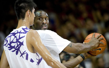 NBA basketball player Kobe Bryant of the Los Angeles Lakers shows his moves to a young player in Hong Kong, south China, July 24, 2009. Bryant was in Hong Kong as part of his Asia tour. [Xinhua]