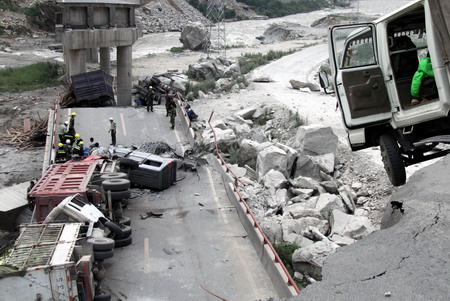 Rescuers work at the scene as a landslide cripples an artery bridge in Wenchuan County, epicenter of last year's May 12th earthquake, in southwest China's Sichuan province Saturday July 25, 2009. [Xinhua]