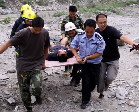 Rescuers carry an injured man as a landslide cripples an artery bridge in Wenchuan County, epicenter of last year's May 12th earthquake, in southwest China's Sichuan province Saturday July 25, 2009. [Xinhua]