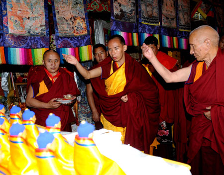 The 11th Panchen Lama Bainqen Erdini Qoigyijabu (C), one of the two most senior living Buddhas in Tibetan Buddhism, prays with other lamas during a ceremony for his receiving the bhikku (monk) ordination at Tashilhunpo Monastery in Xigaze, southwest China's Tibet Autonomous Region, July 25, 2009.
