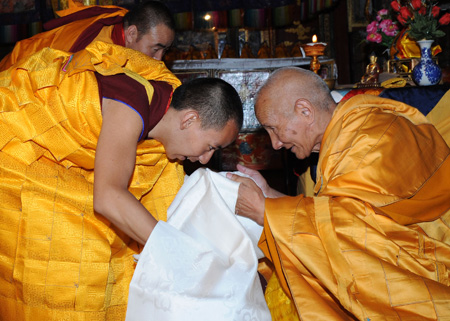 The 11th Panchen Lama Bainqen Erdini Qoigyijabu (L), one of the two most senior living Buddhas in Tibetan Buddhism, presents a 'hada', a white scarf symbolizing Tibetan best wishes, to his sutra teacher Jamyang Gyamco during a ceremony for his receiving the bhikku (monk) ordination at Zhaxi Lhunbo Lamasery in Xigaze, southwest China's Tibet Autonomous Region, July 25, 2009. 