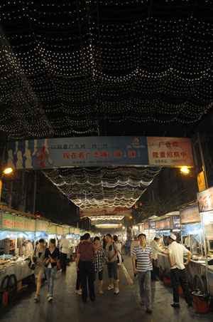 People walk along the street at the most famous night fair in Urumqi, capital of northwest China's Xinjiang Uygur Autonomous Region, July 25, 2009. The Wuyi Starlight night fair, the biggest and most famous night fair in Urumqi, reopened here on July 21 for the first time since the deadly July 5 riot in the city. 