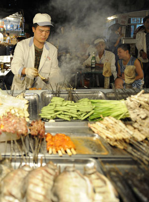 A vendor makes snacks at the most famous night fair in Urumqi, capital of northwest China's Xinjiang Uygur Autonomous Region, July 25, 2009. The Wuyi Starlight night fair, the biggest and most famous night fair in Urumqi, reopened here on July 21 for the first time since the deadly July 5 riot in the city.