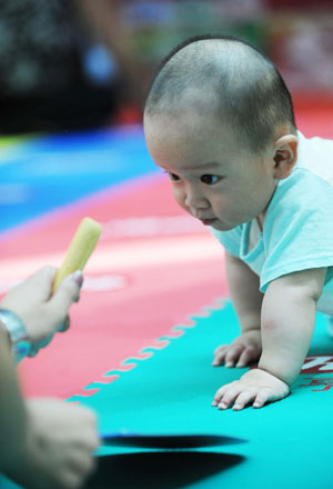 A baby creeps during a baby talent show in Harbin, capital of northeast China's Heilongjiang Province, July 26, 2009. [Wang Jianwei/Xinhua]
