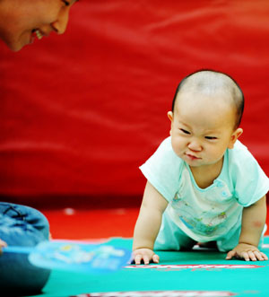 A baby creeps during a baby talent show in Harbin, capital of northeast China's Heilongjiang Province, July 26, 2009. [Wang Jianwei/Xinhua] 